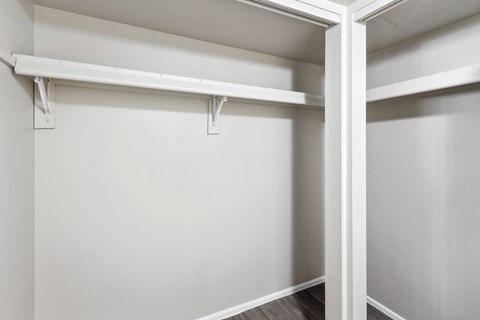 an empty closet in a home with white walls and wood floors